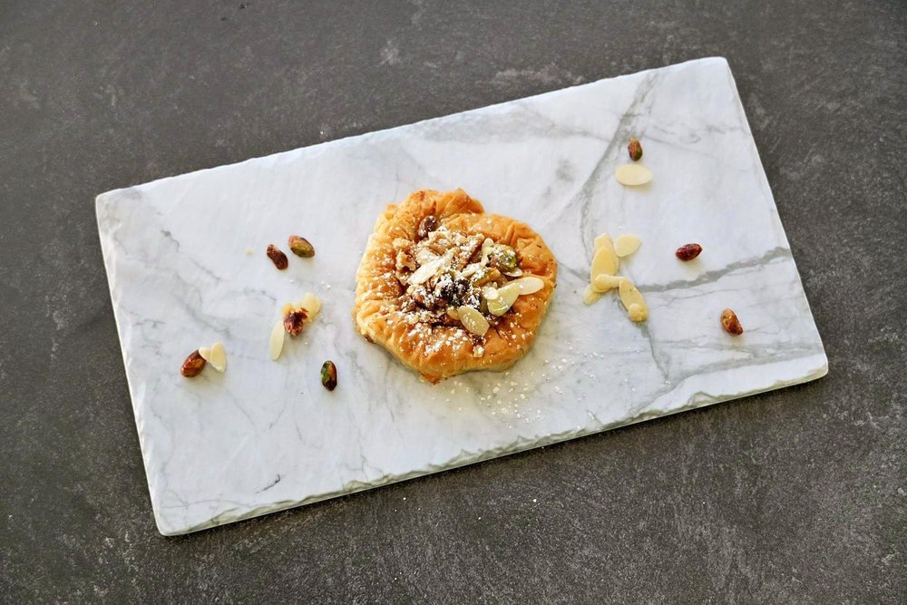 A spread of Arabic pastries — baklava, kanafeh, ma'amoul — fresh from the Grand Kitchen oven.